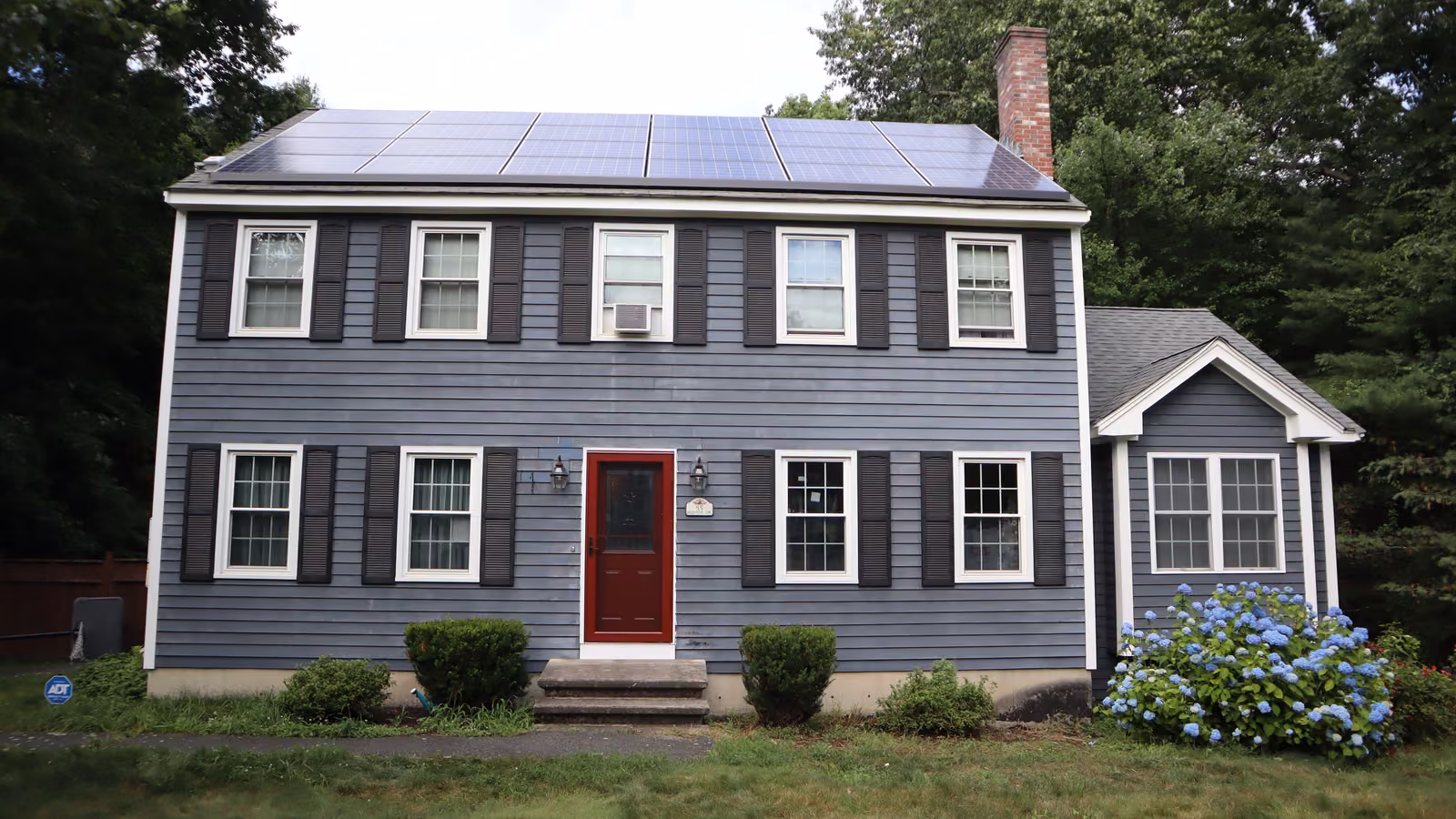 New red entry door on a two-story colonial house exterior