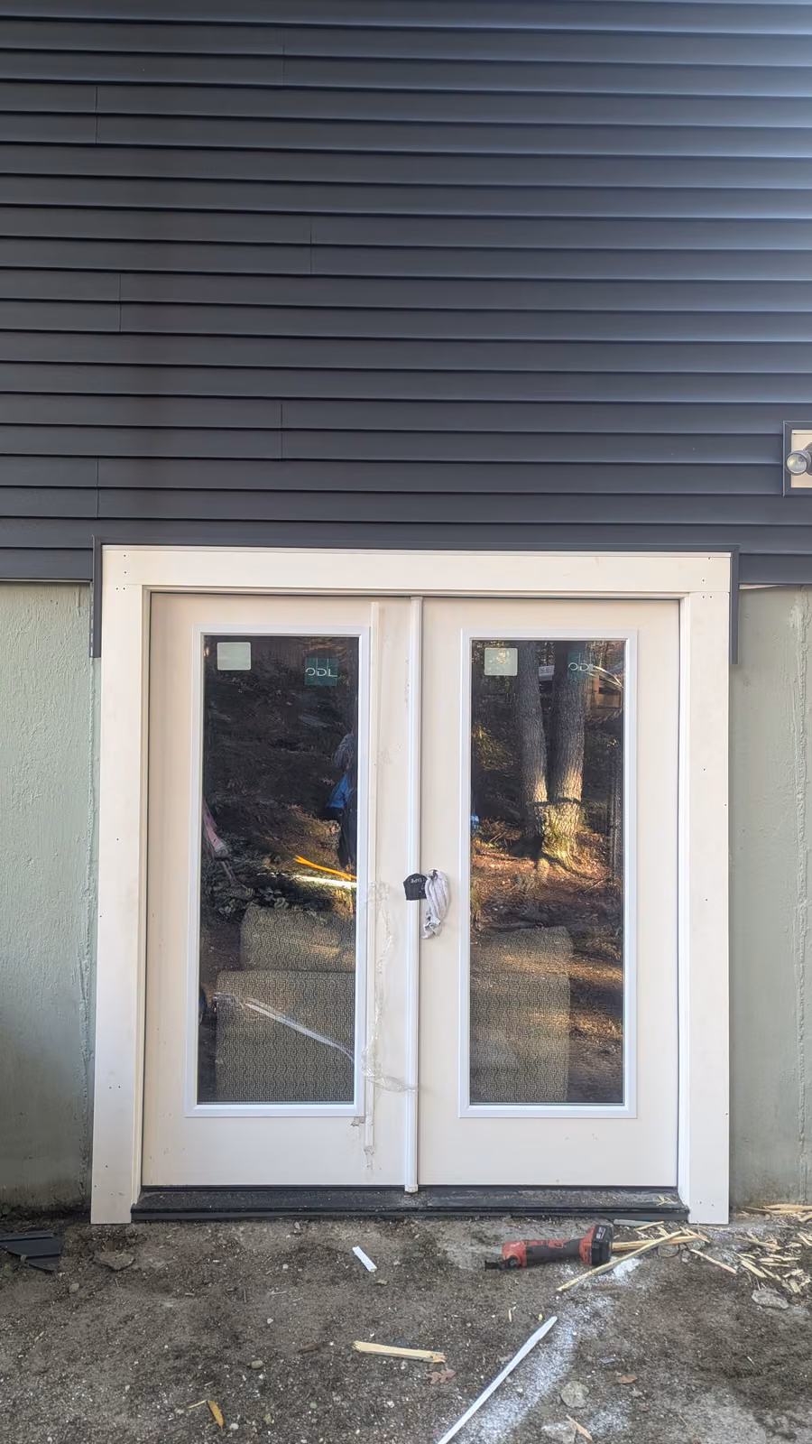 White French double doors with full-lite glass panels on dark gray siding