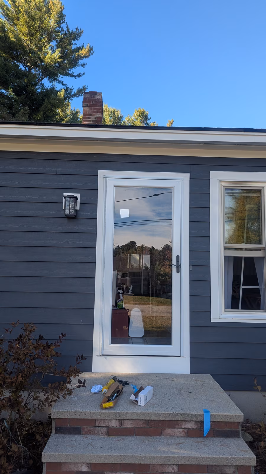 Full-view glass storm door installed on a gray siding home with clean trim