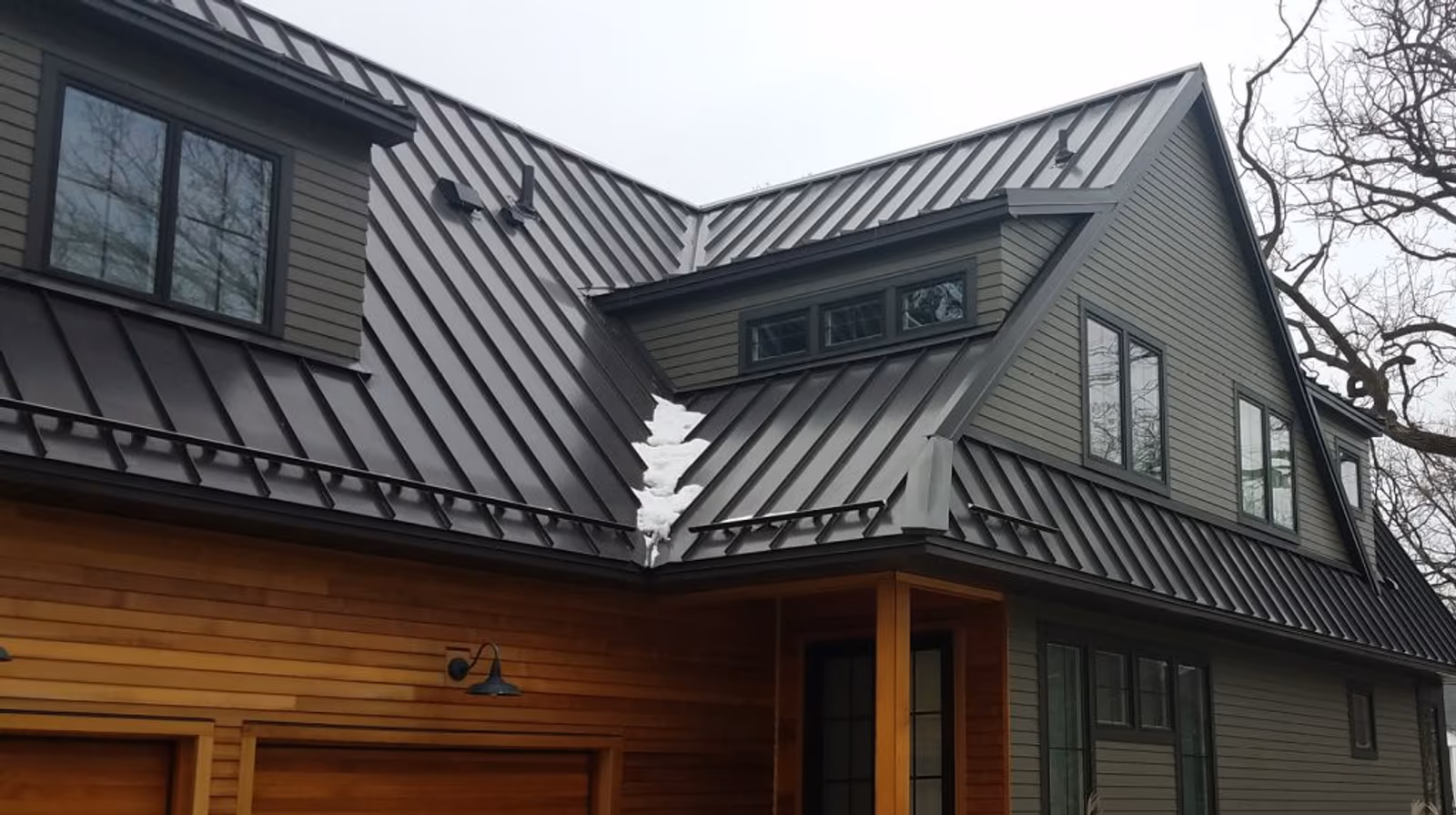 Modern home with a dark standing-seam metal roof and mixed wood and gray siding