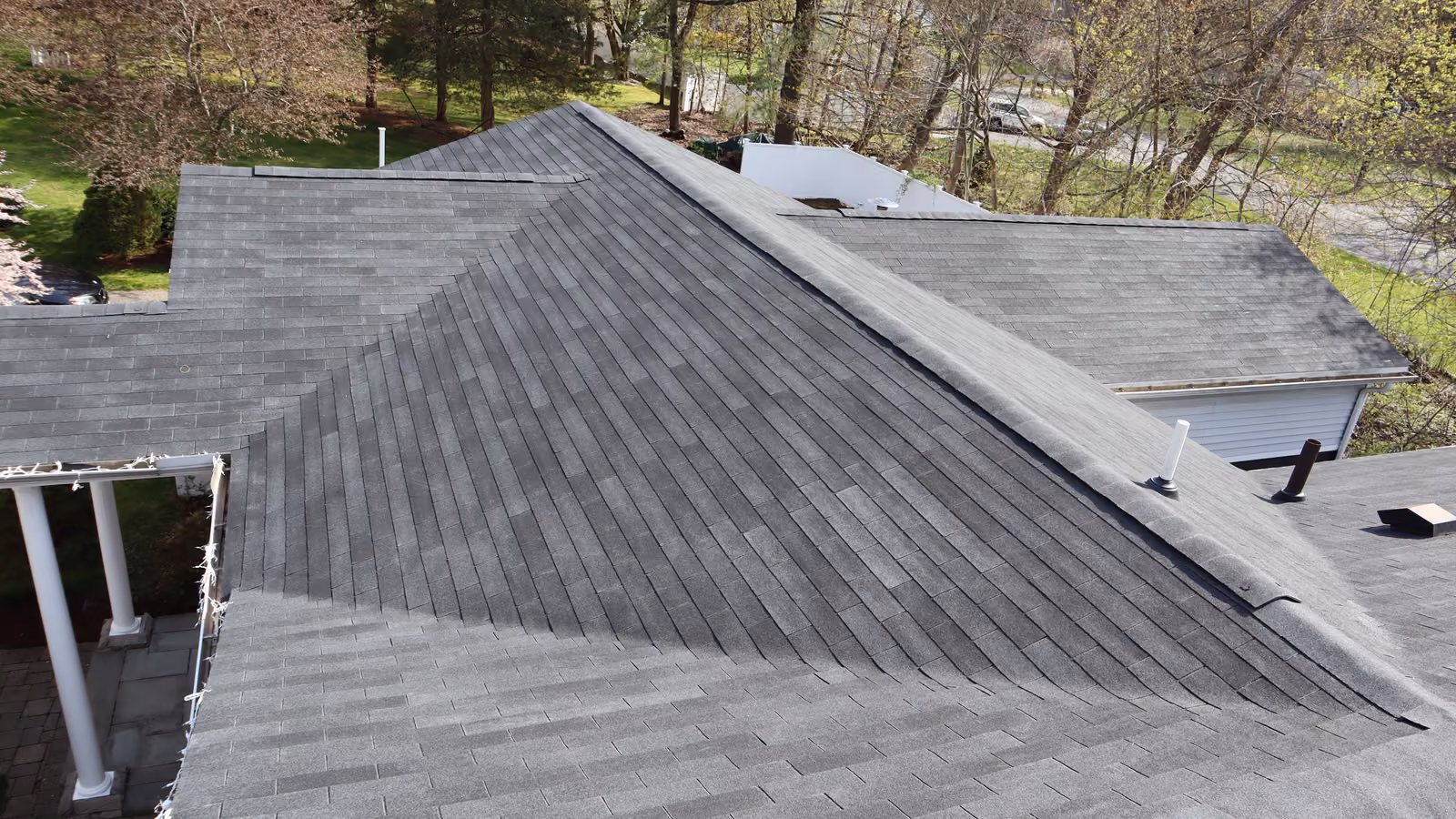Close-up aerial of a charcoal hip roof showing precise shingle alignment