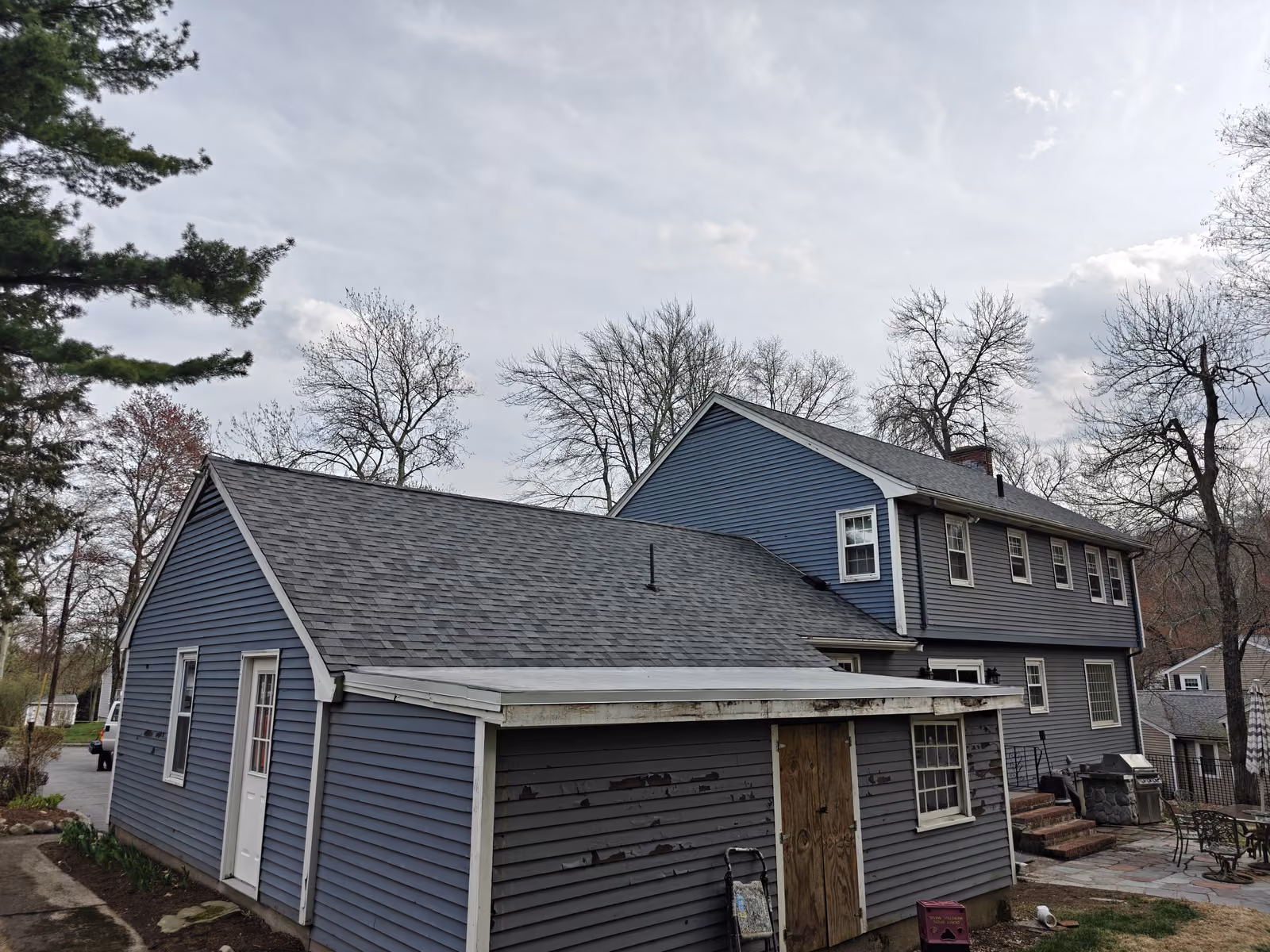 Completed gray asphalt shingle roof on a two-story blue colonial home