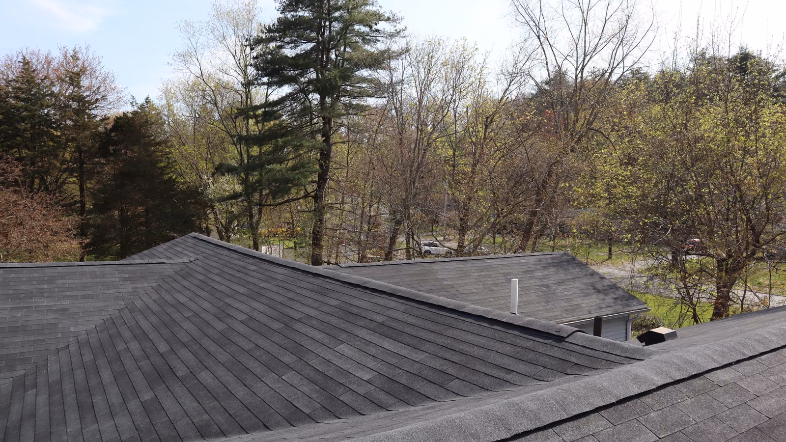 Hip ridge lines meeting at a tight clean peak on a dark gray shingle roof