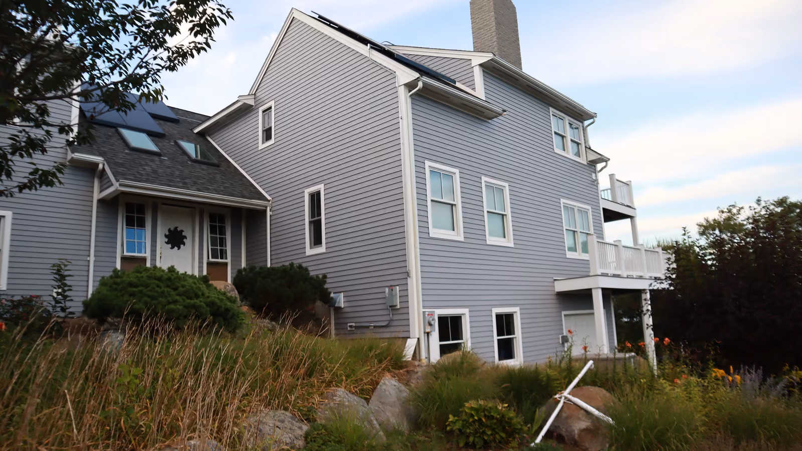 Brookline home with new gray lap siding and white trim across two facades