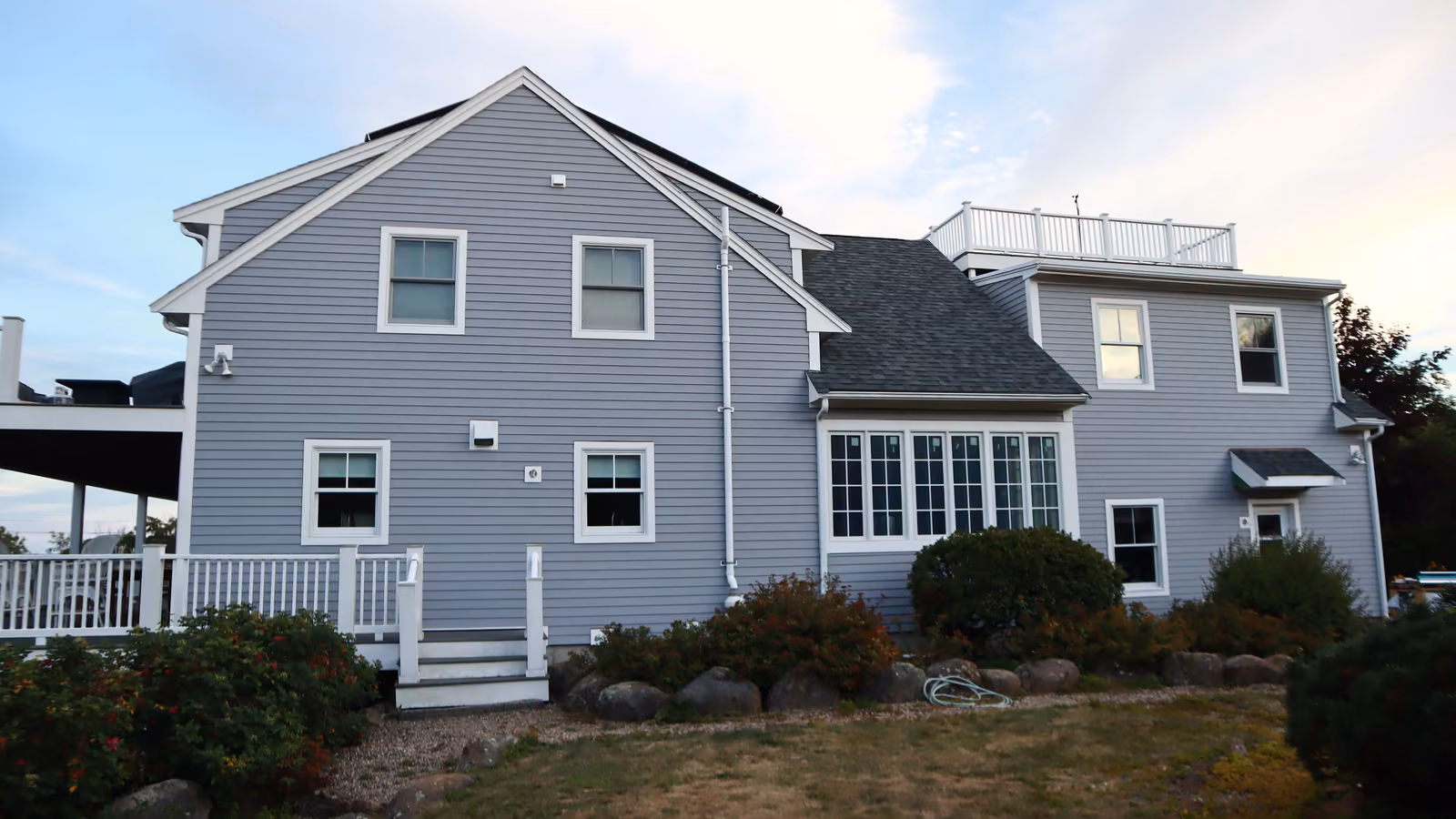 Rear elevation of a Brookline home with gray lap siding across multiple gables