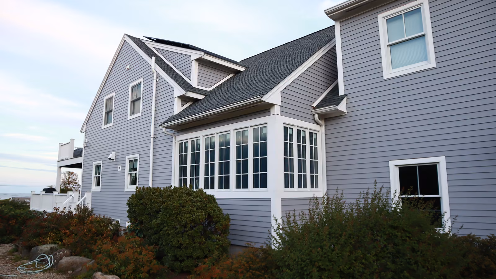 Side view of a Brookline home with a sunroom bay and new gray siding