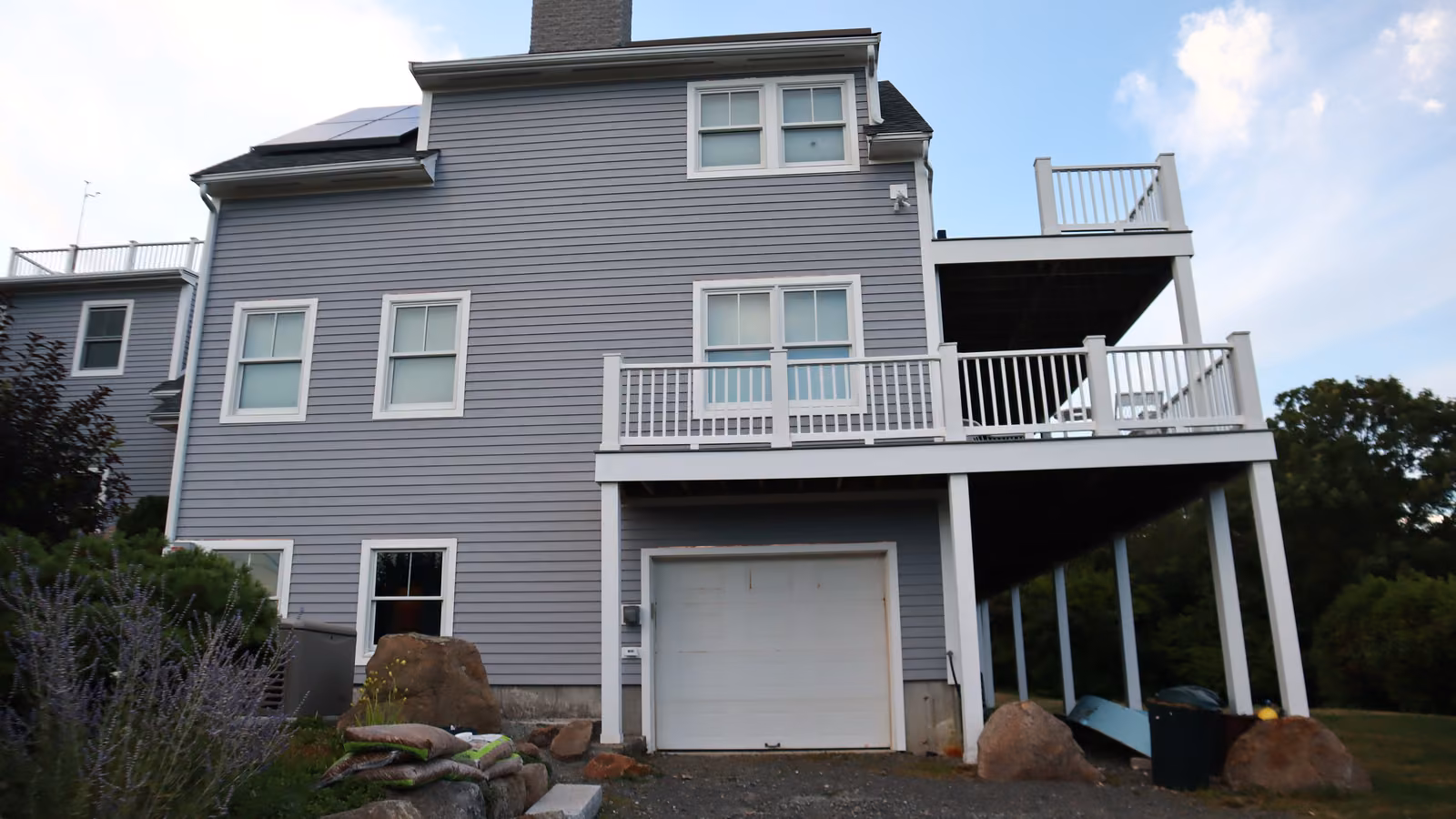 Three-story side elevation with garage and elevated deck after re-siding