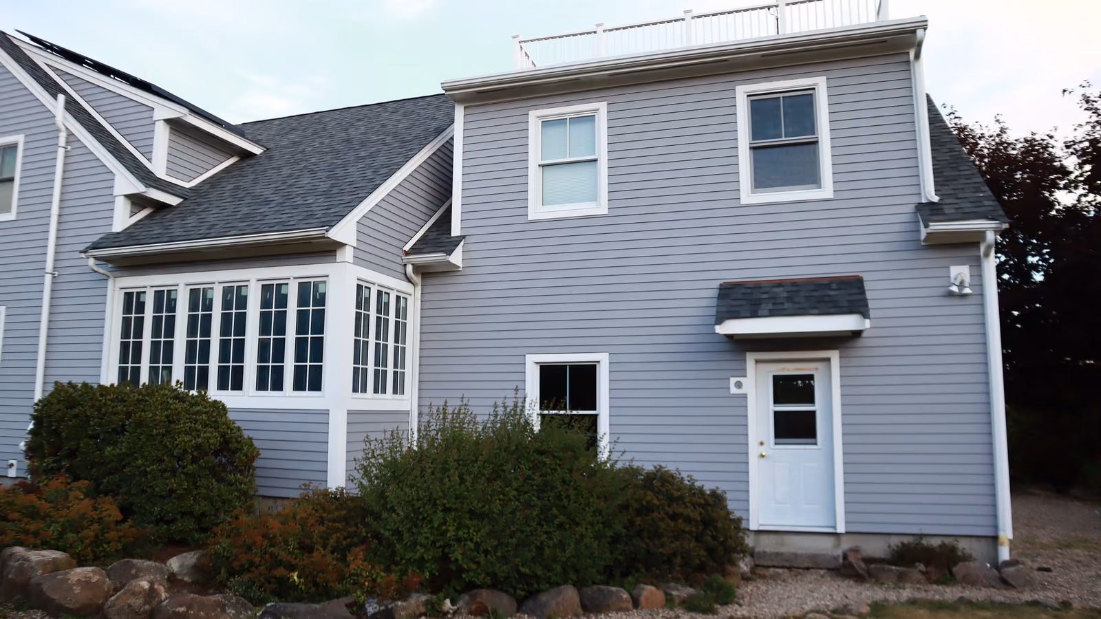 Front entry of a Brookline home with new gray lap siding and bay windows