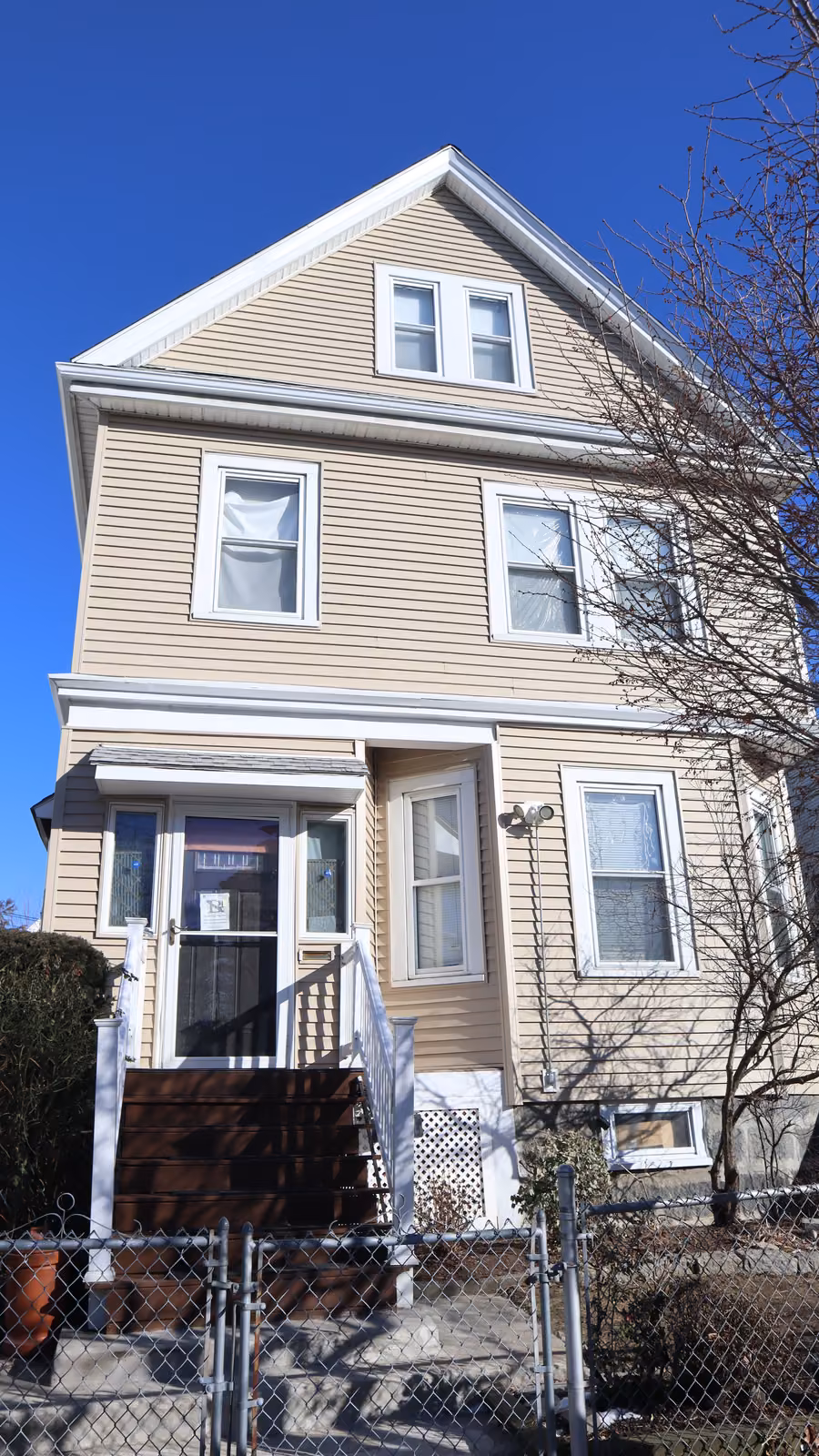 New tan vinyl siding on a three-story home in Dorchester, MA — front facade