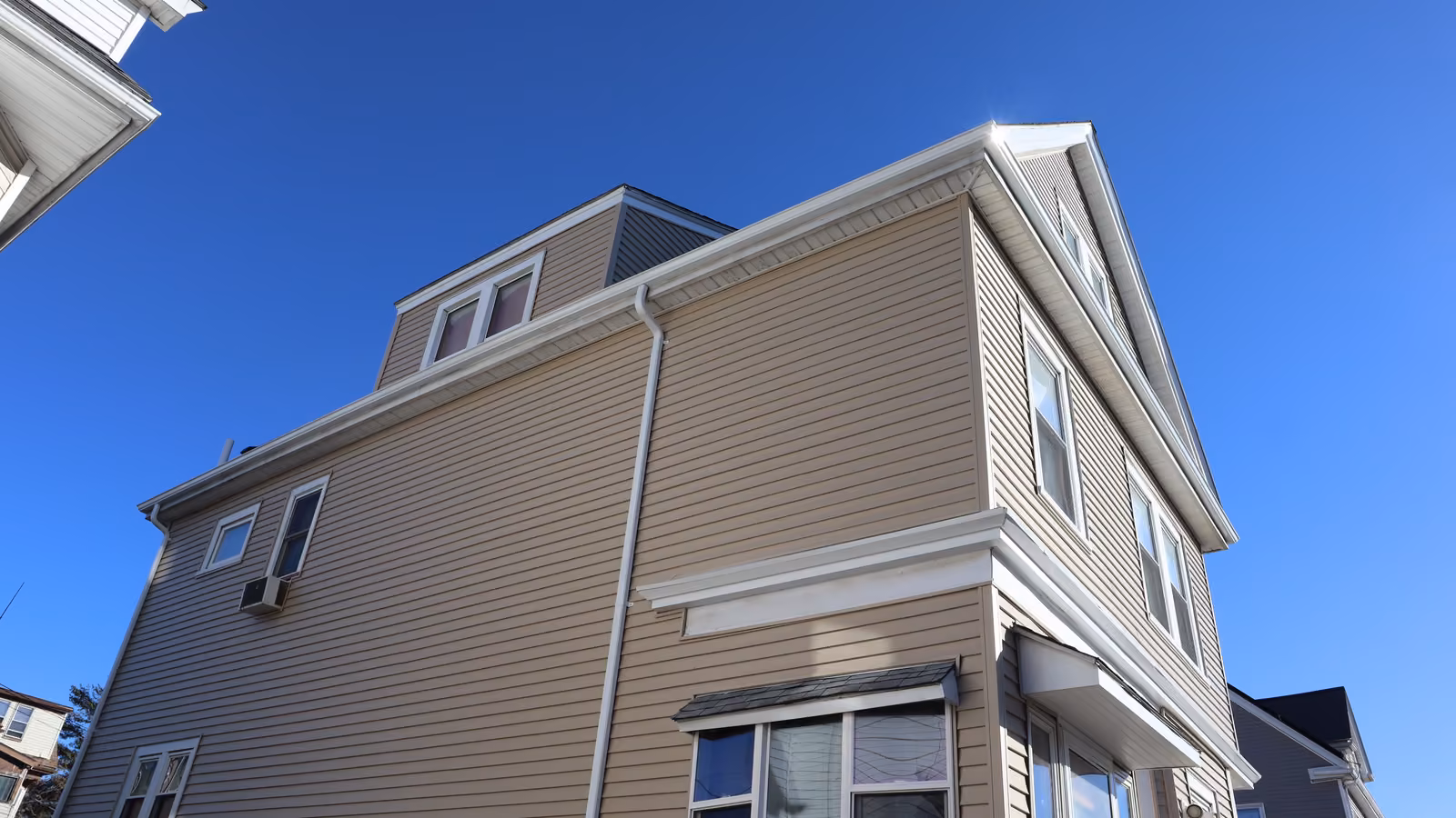 Back corner of the finished siding project with clad dormer and new gutter system