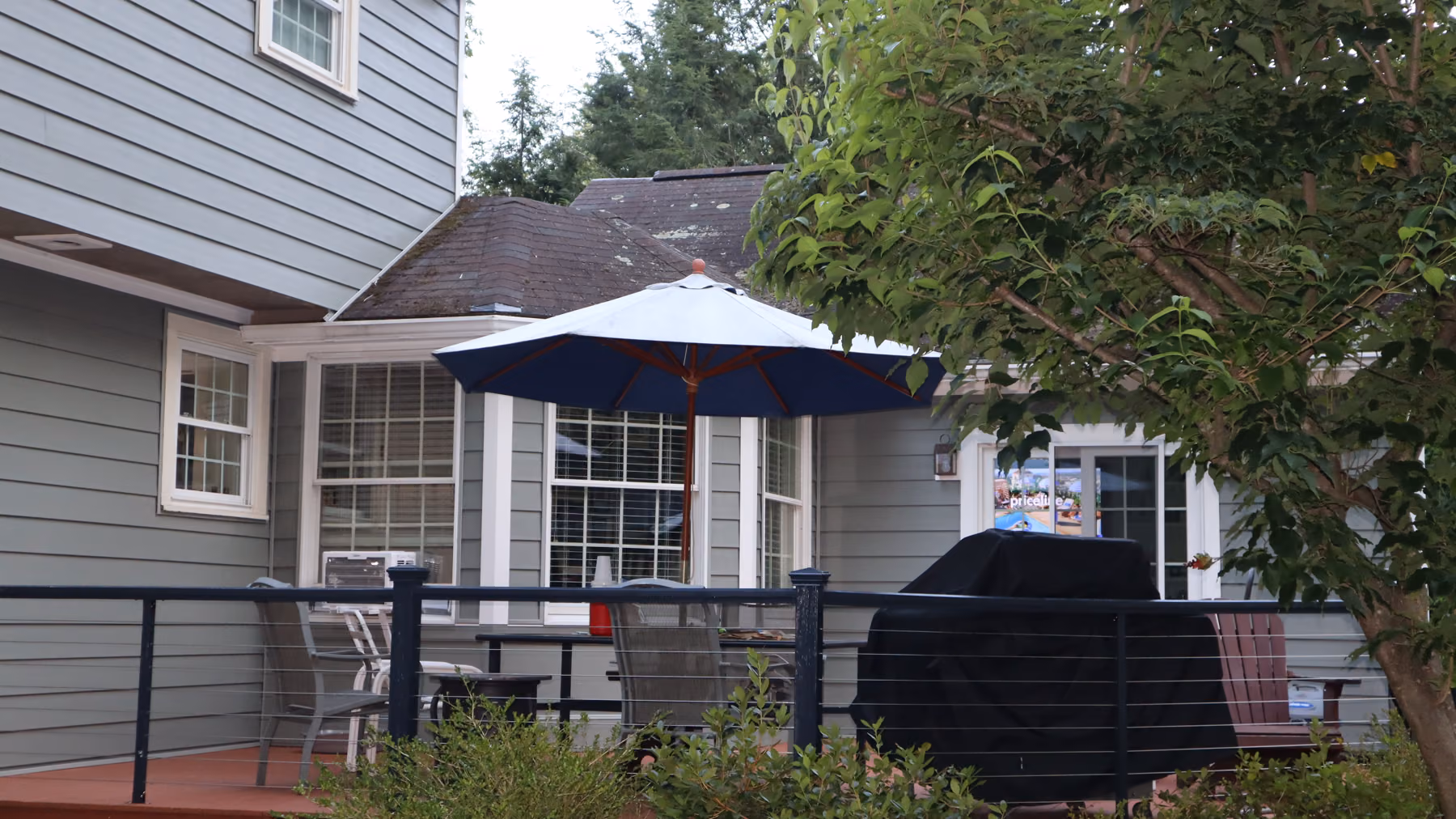 Rear corner of the home with green siding, skylights on the roof and a clean white trim line