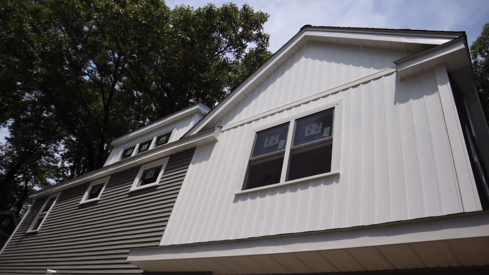 White board-and-batten siding on an upper gable above horizontal vinyl siding