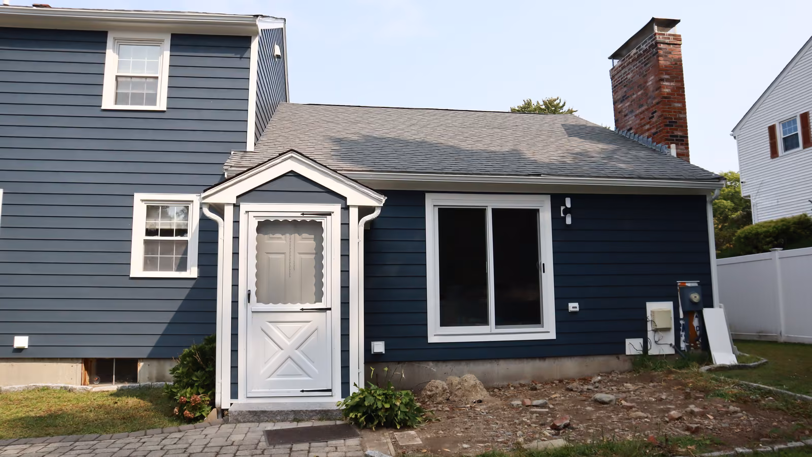 Rear addition clad in navy siding with a white entry door