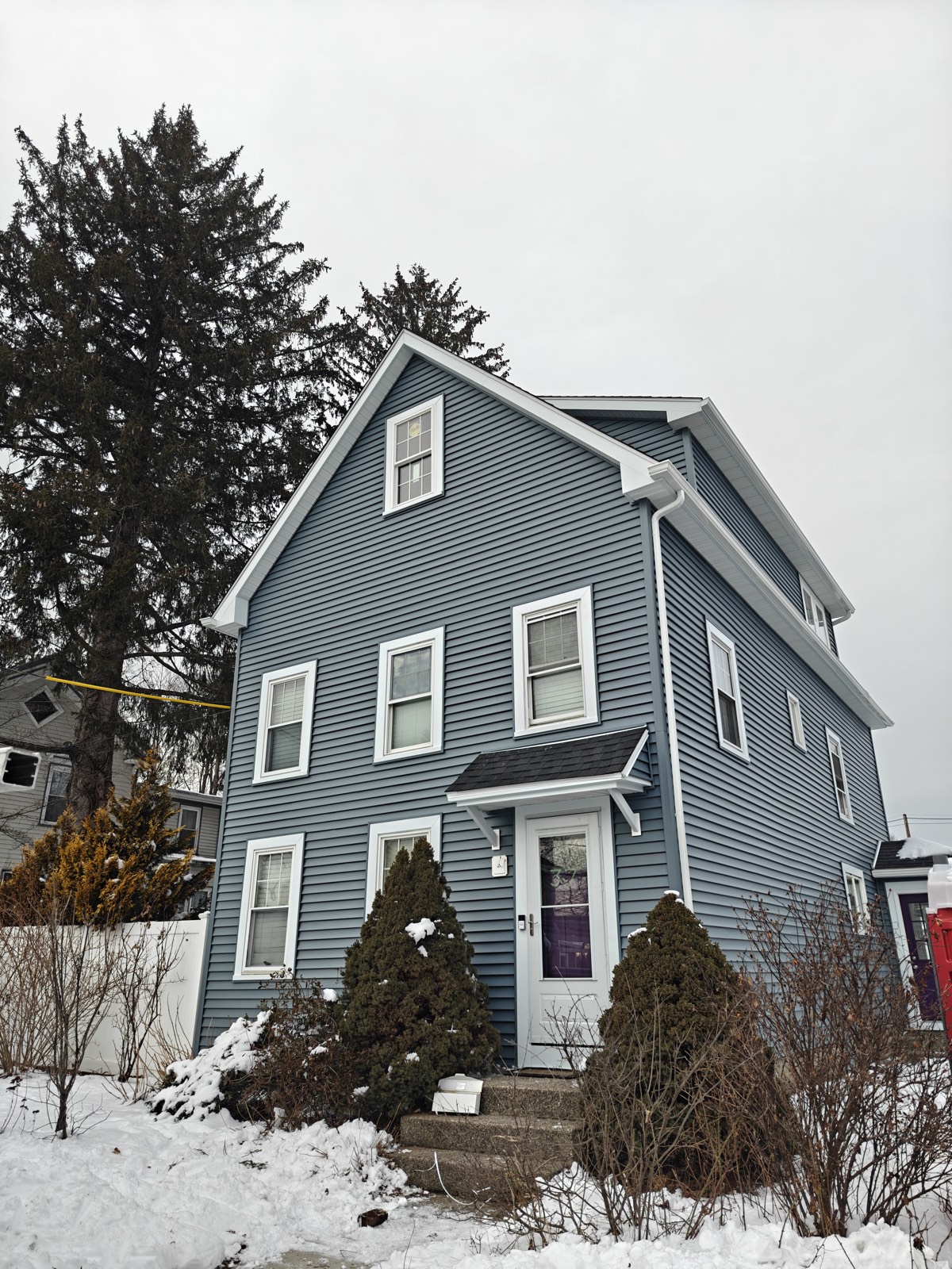 Front elevation of a gray-blue colonial home with new siding and white trim