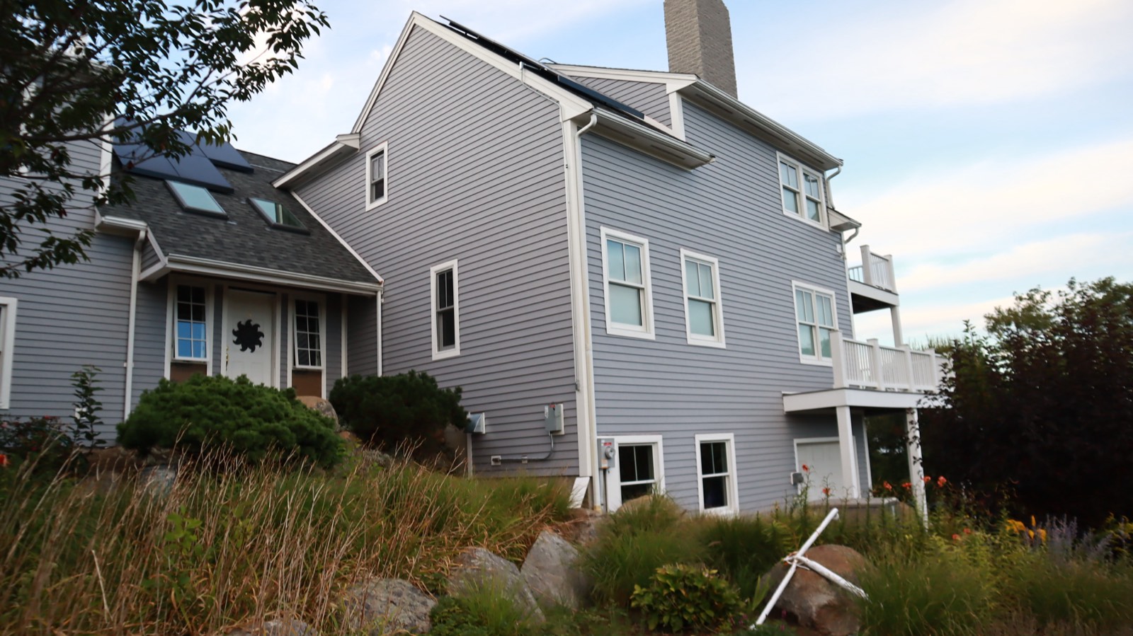 Coastal home in new lap siding with a meadow foreground in warm evening light