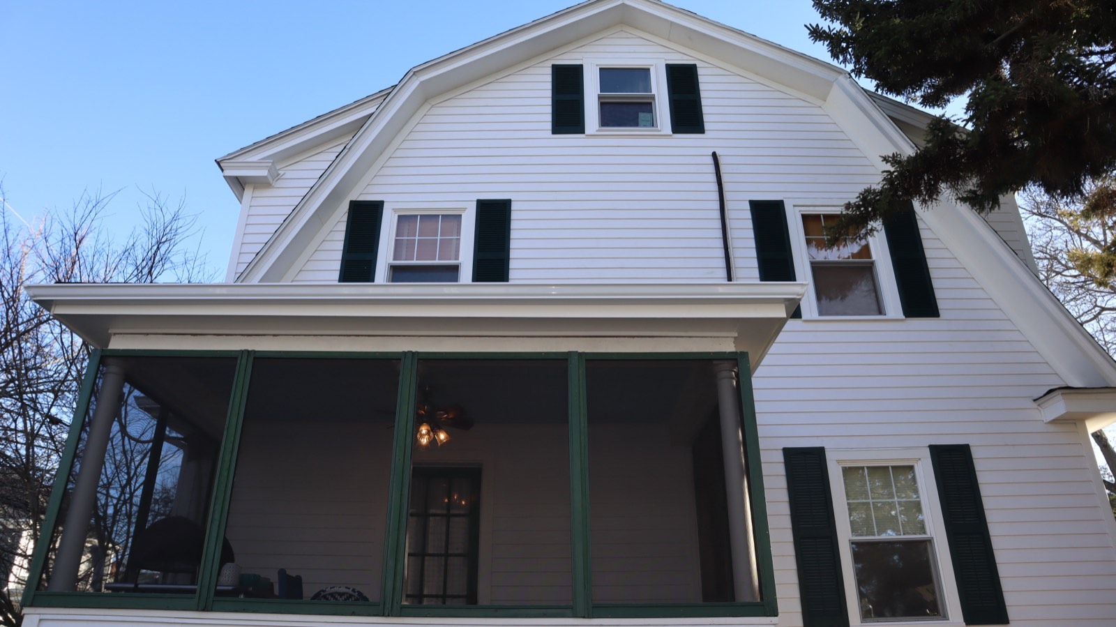 Symmetric white gable and porch with new siding under a blue sky