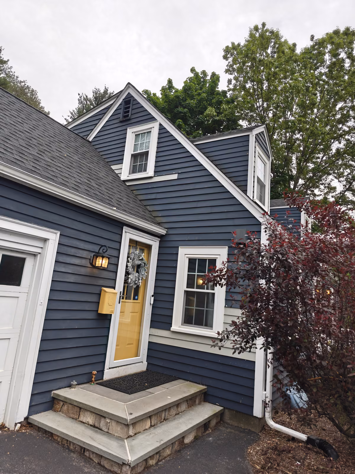 Blue Cape Cod home with newly installed white double-hung windows and matching trim