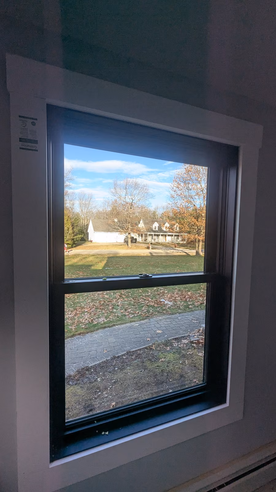 Newly installed black double-hung window with crisp white interior trim