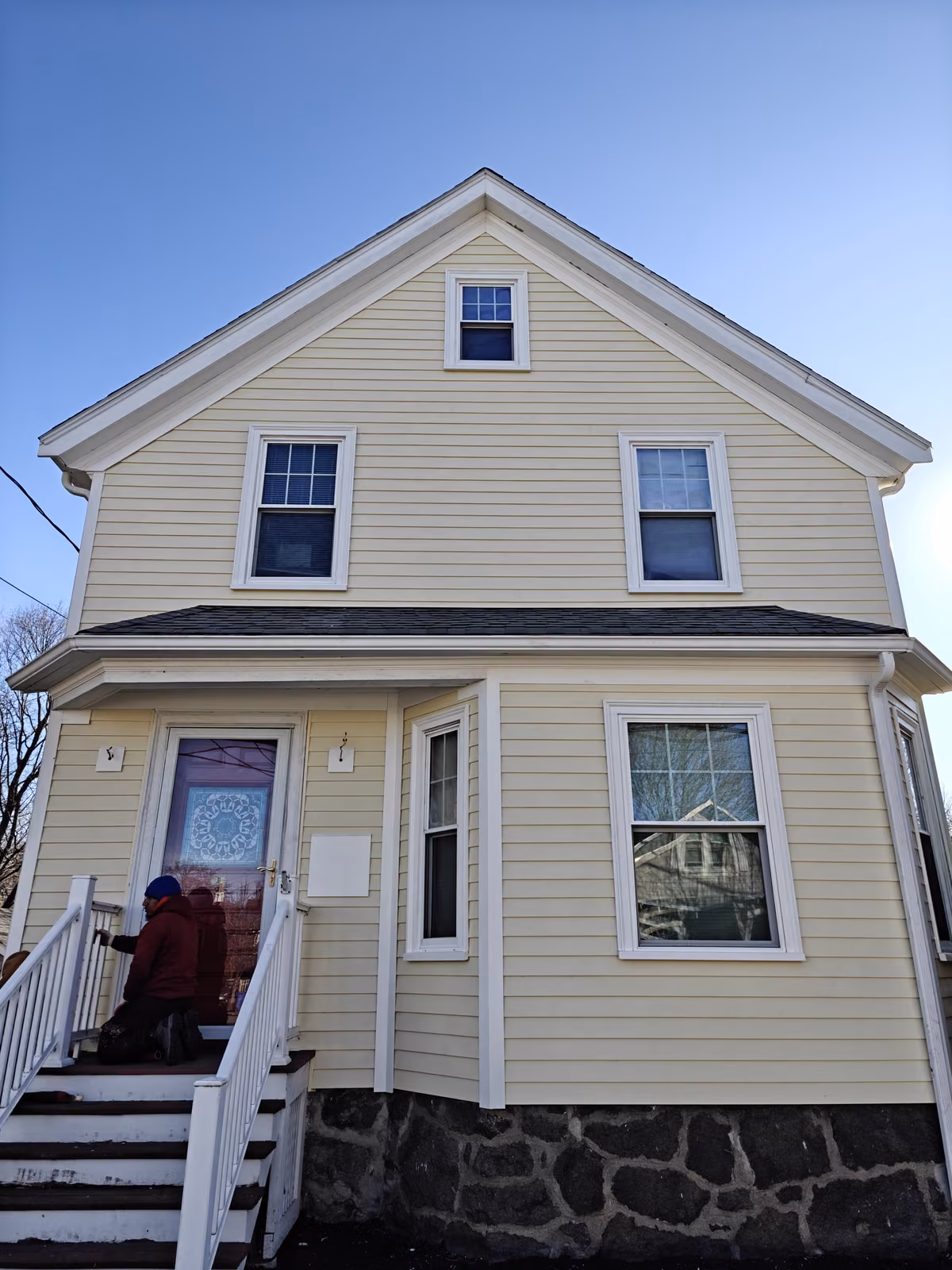 Two-story colonial home with white double-hung windows replaced throughout the facade