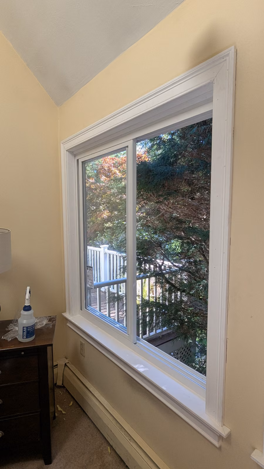 White sliding window installed in a bedroom with clean interior trim