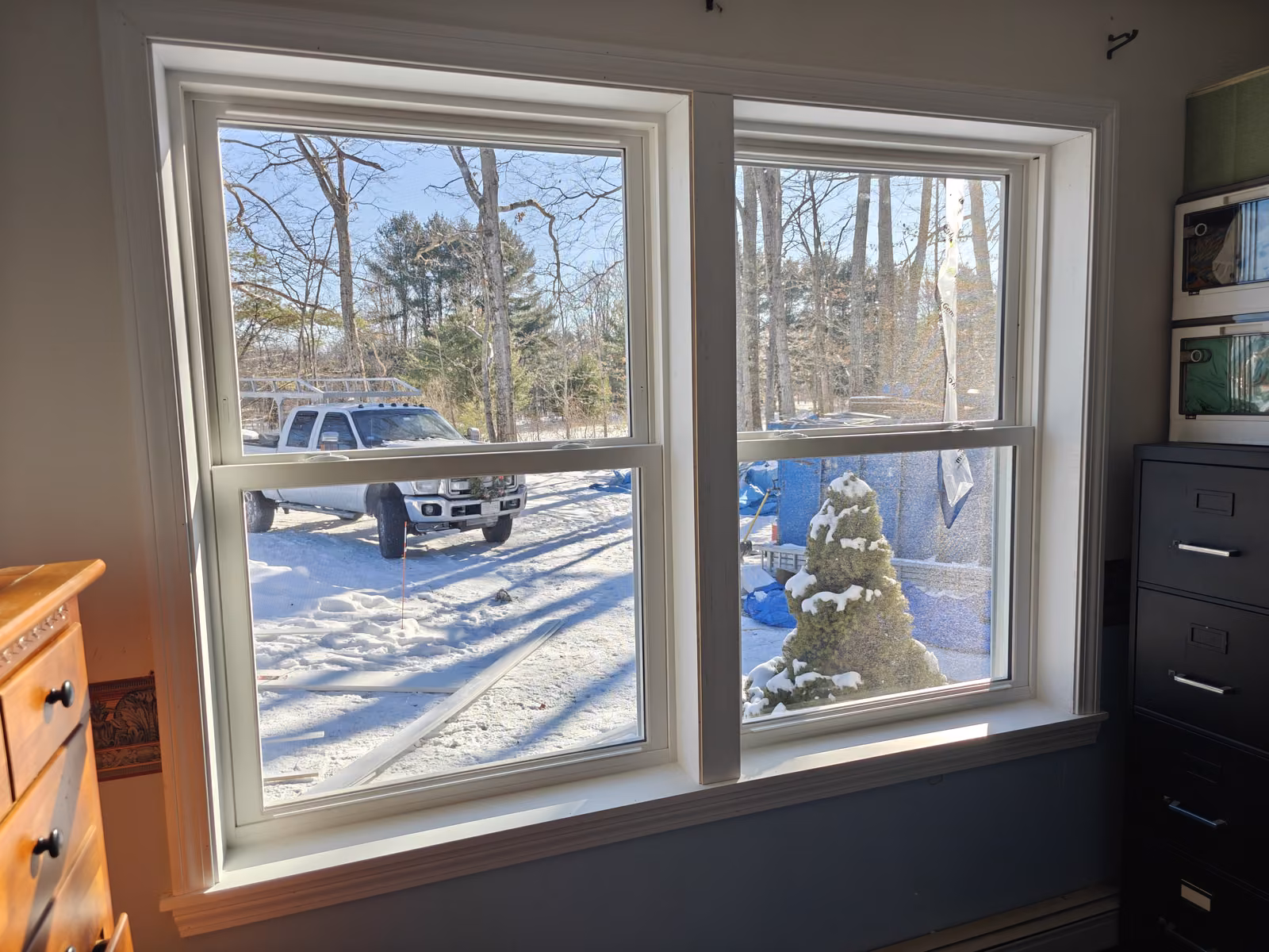 Paired white double-hung windows in a finished room with new trim